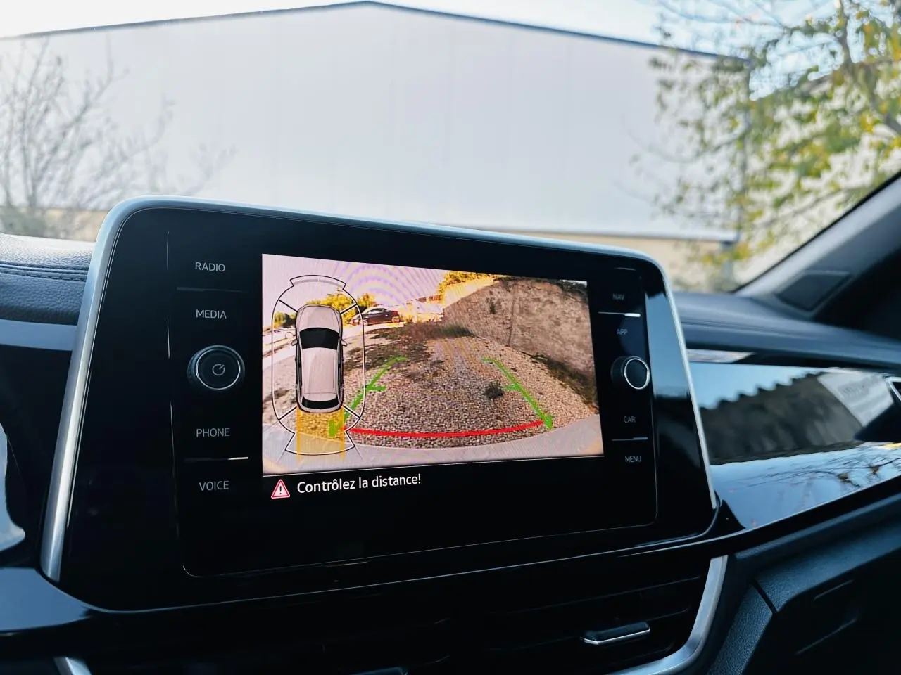 Écran tactile intérieur du Volkswagen T-Roc 2024 affichant la caméra de recul avec alertes de distance.