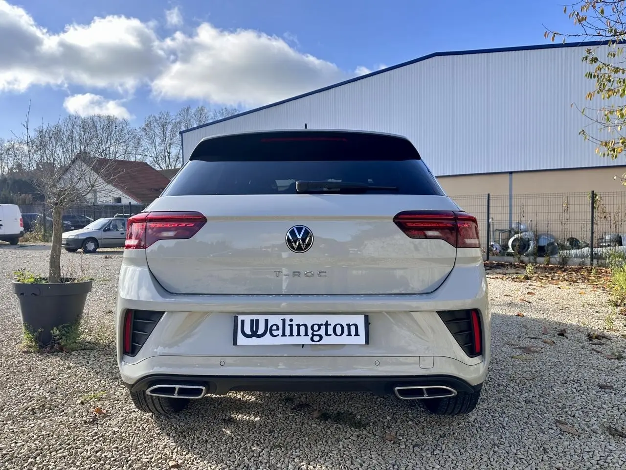 Vue arrière d'un Volkswagen T-Roc gris 2024 avec double sortie d'échappement et logo R-Line visible sur le coffre.
