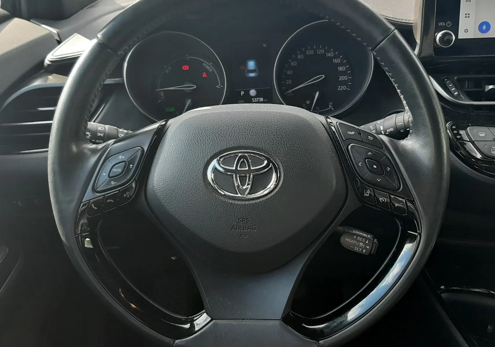Vue intérieure avant du Toyota C-HR 1.8 Hybrid 122 Design 2023 noir, tableau de bord et volant multifonctions visibles.