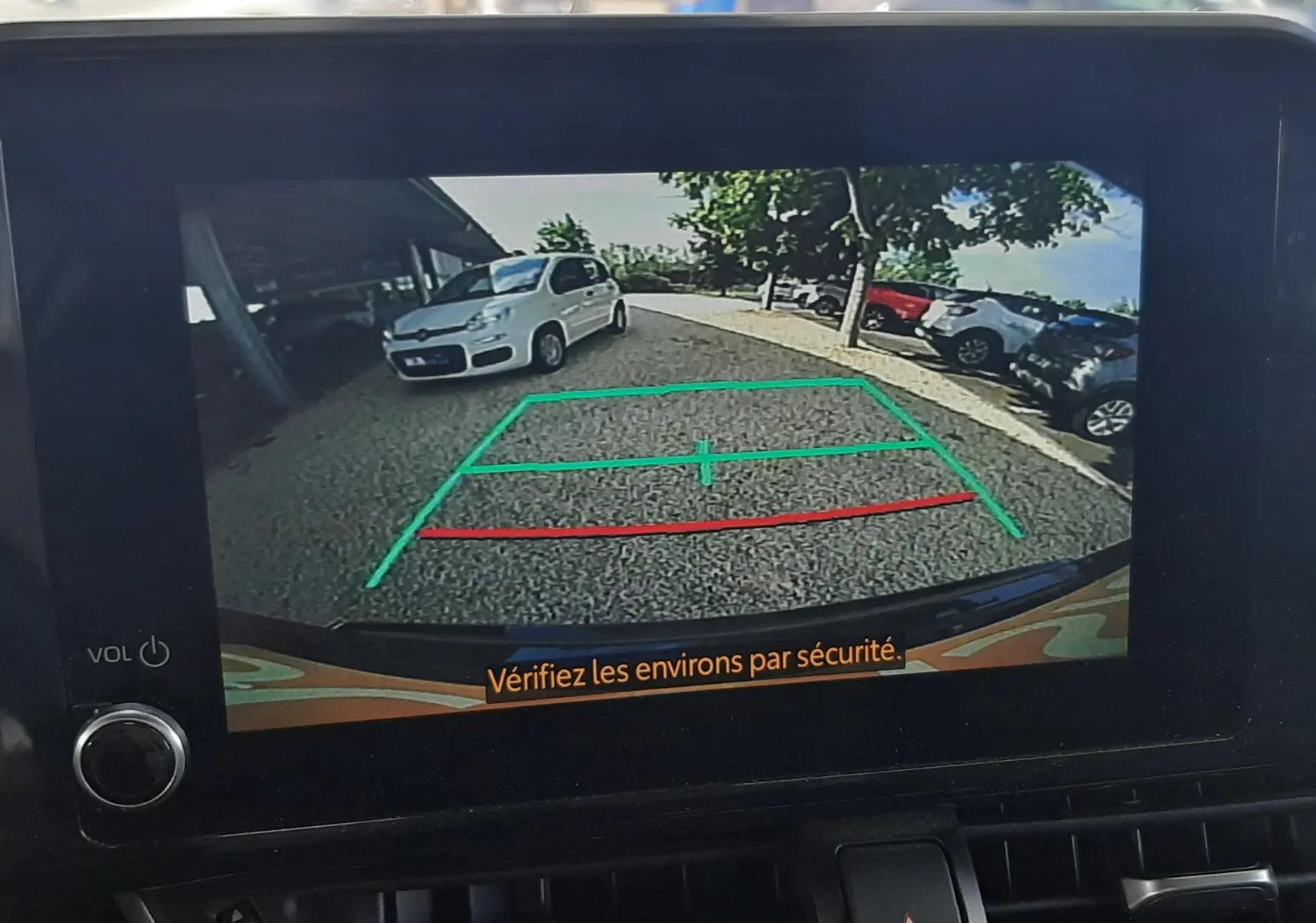 Vue rapprochée de la console centrale noire du Toyota C-HR 1.8 Hybrid 2023 avec écran tactile et commandes climatisation digitales.