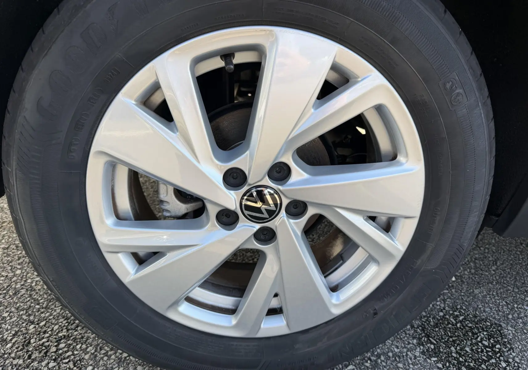 Gros plan sur la jante alliage argentée 16 pouces avec logo Volkswagen au centre, montée sur pneu Goodyear.