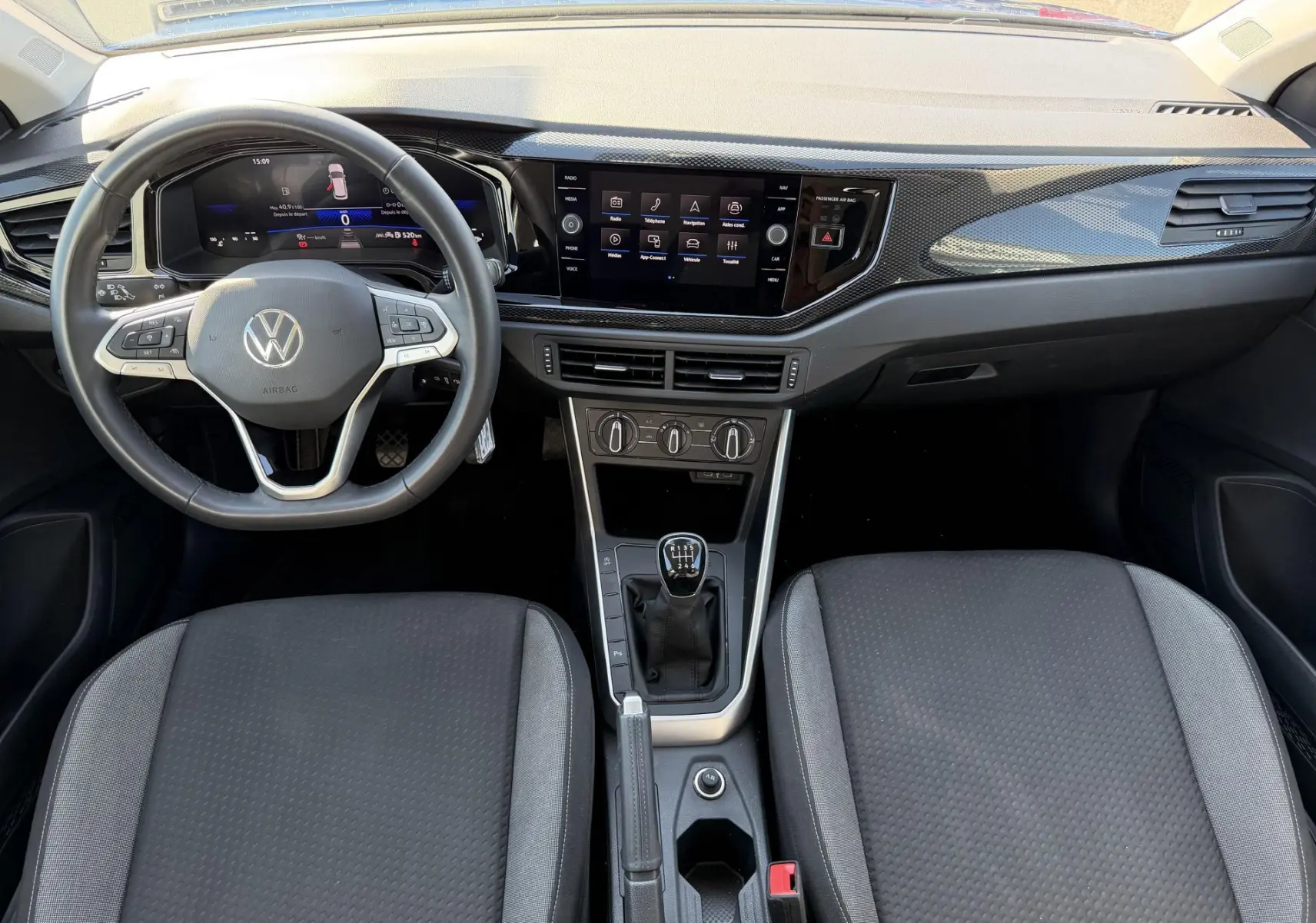 Vue intérieure avant du Volkswagen Taigo 1.0 TSI 116 BVM6 2025, tableau de bord noir avec volant cuir multifonction et levier manuel.