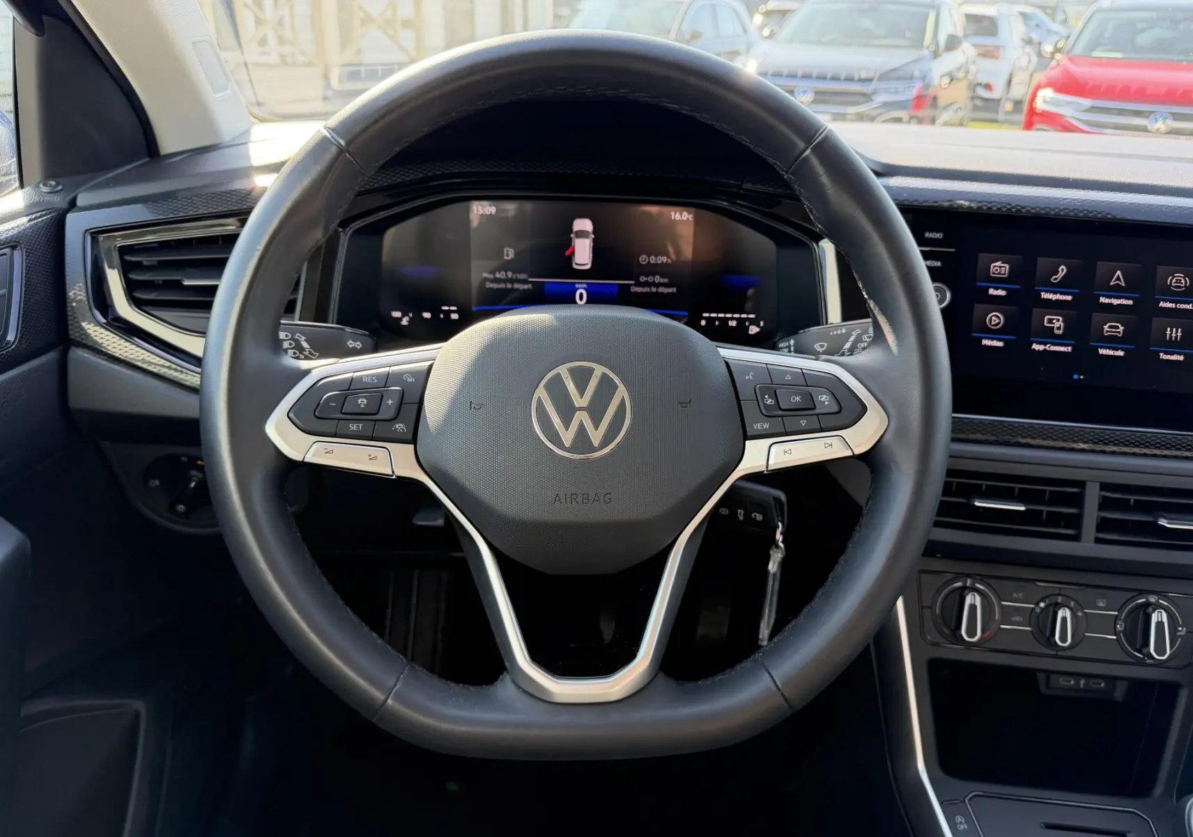 Vue intérieure centrée sur le volant multifonction cuir du Volkswagen Taigo avec tableau de bord digital et écran tactile.