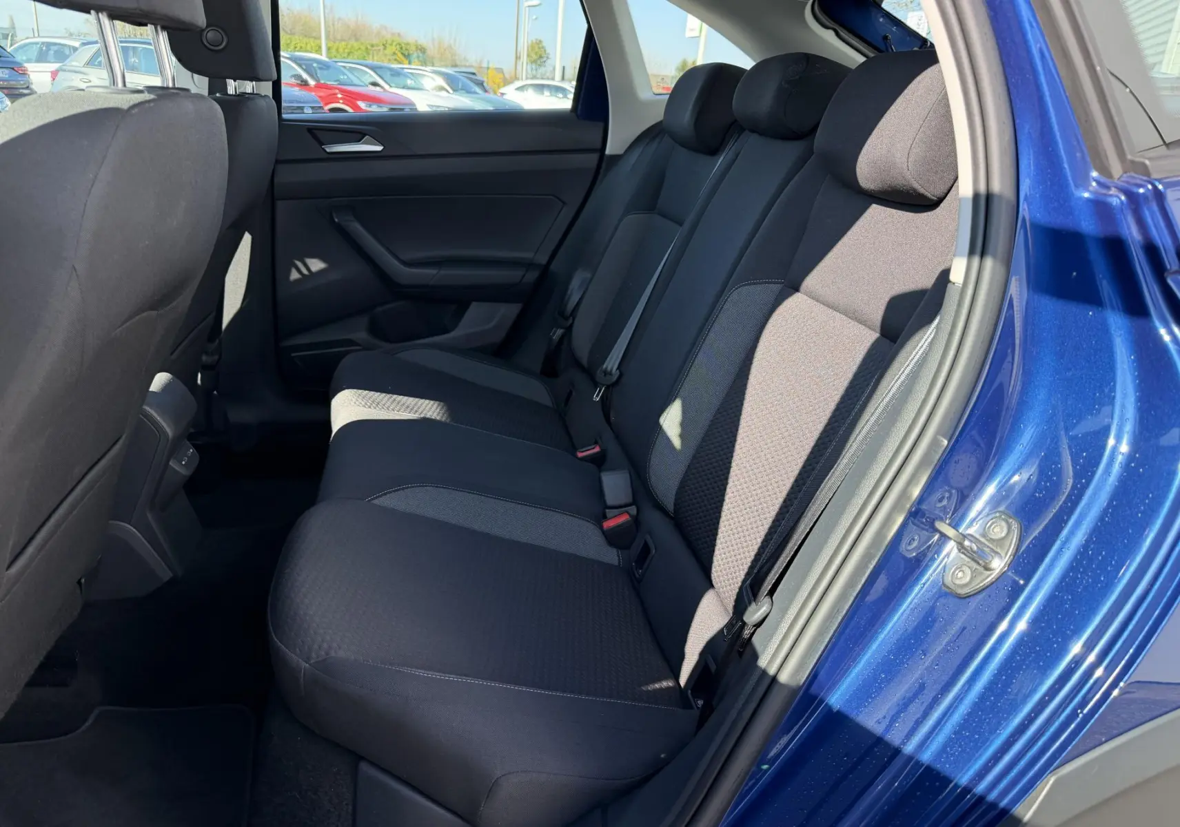Vue intérieure côté droit des sièges arrière noirs du Volkswagen Taigo 2025 en bleu métallisé, porte ouverte.