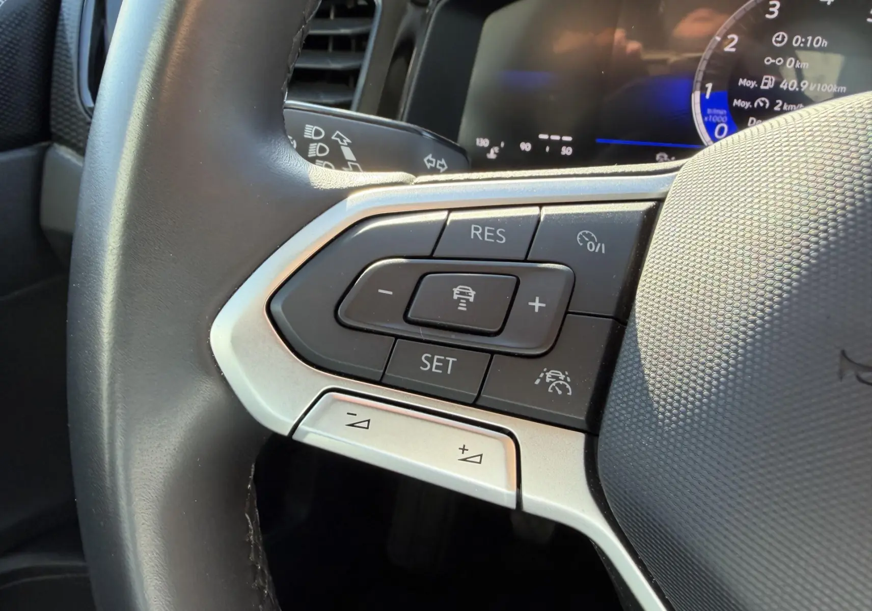 Gros plan sur les commandes du volant cuir à gauche du Volkswagen Taigo 2025, affichage digital en arrière-plan.