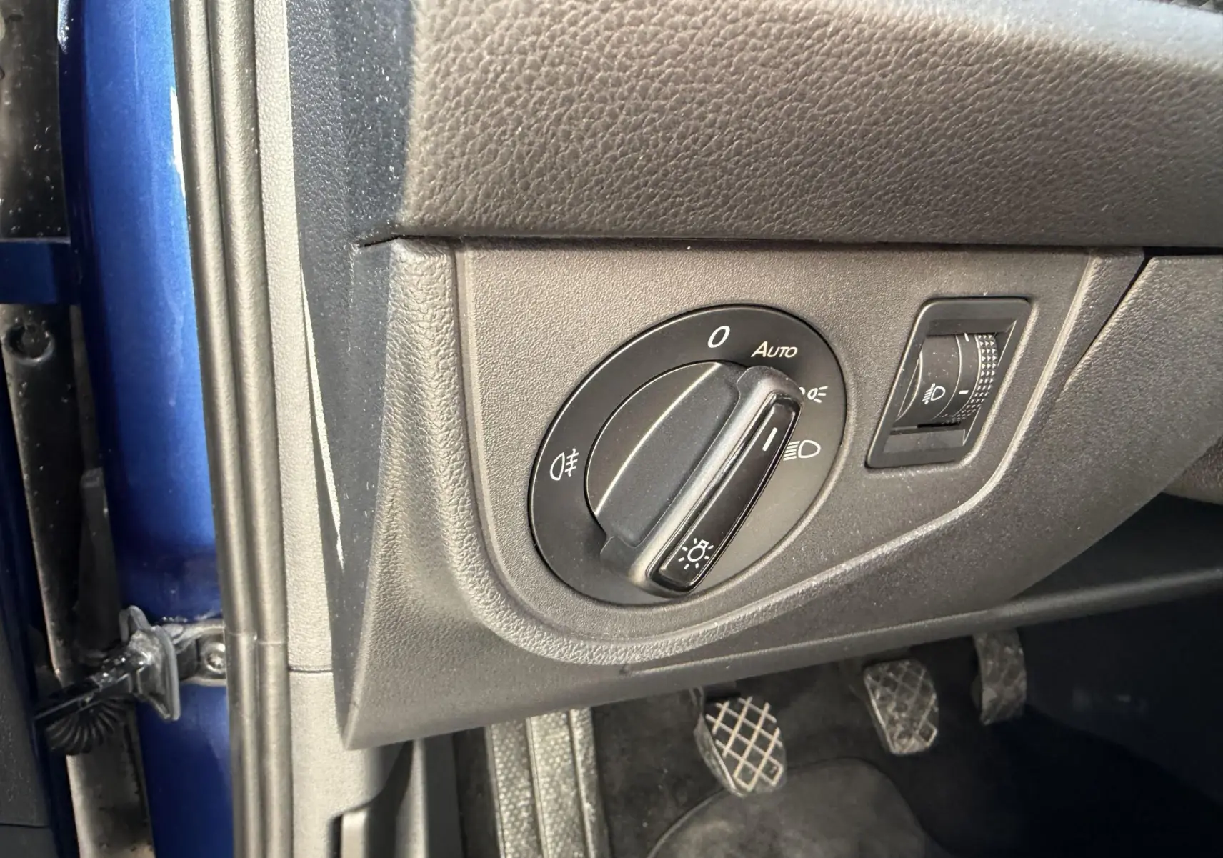 Détail du bouton de commande des phares sur le tableau de bord côté gauche d’un Volkswagen Taigo bleu 2025.