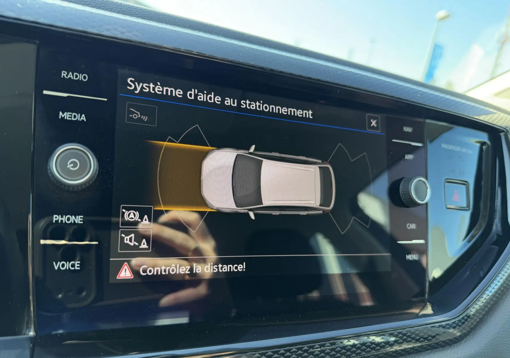 Écran tactile intérieur du Volkswagen Taigo affichant le système d'aide au stationnement avec alertes de distance.