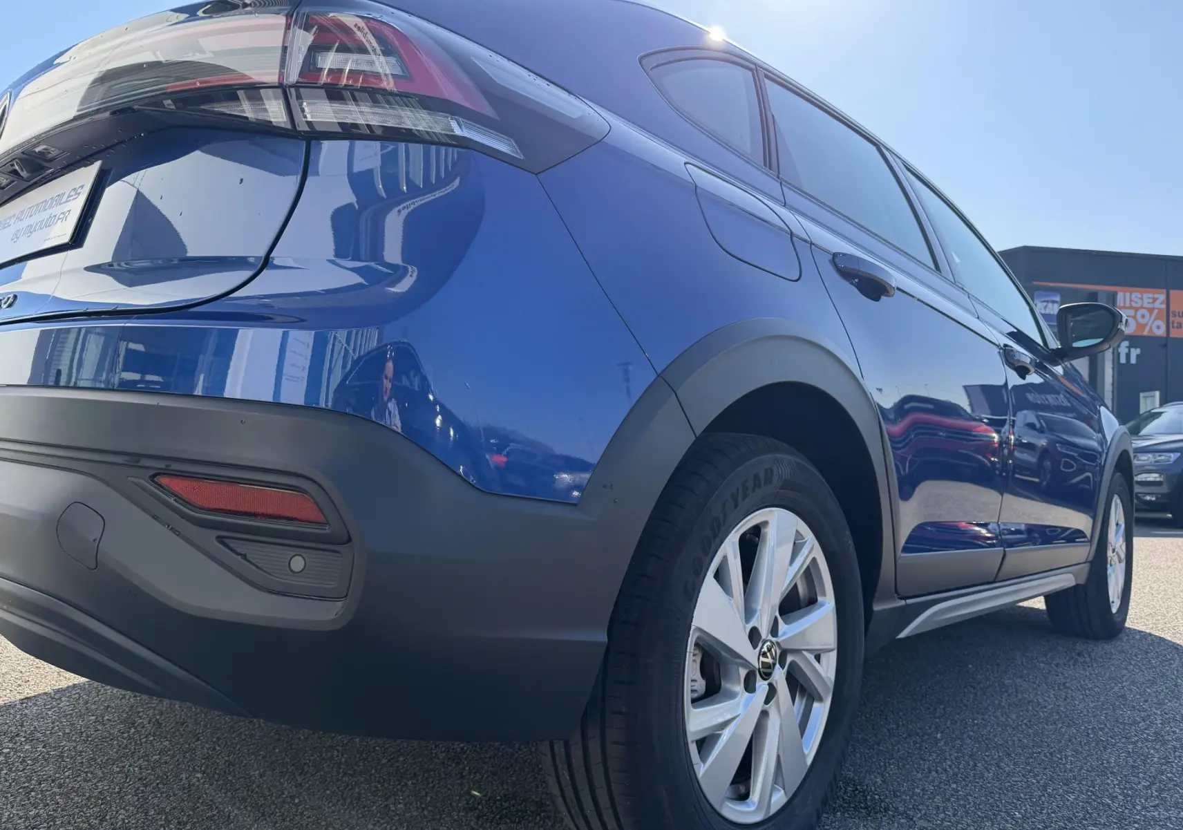 Vue 3/4 arrière droite du Volkswagen Taigo bleu métallisé avec jantes alliage et protections noires sur passages de roues.
