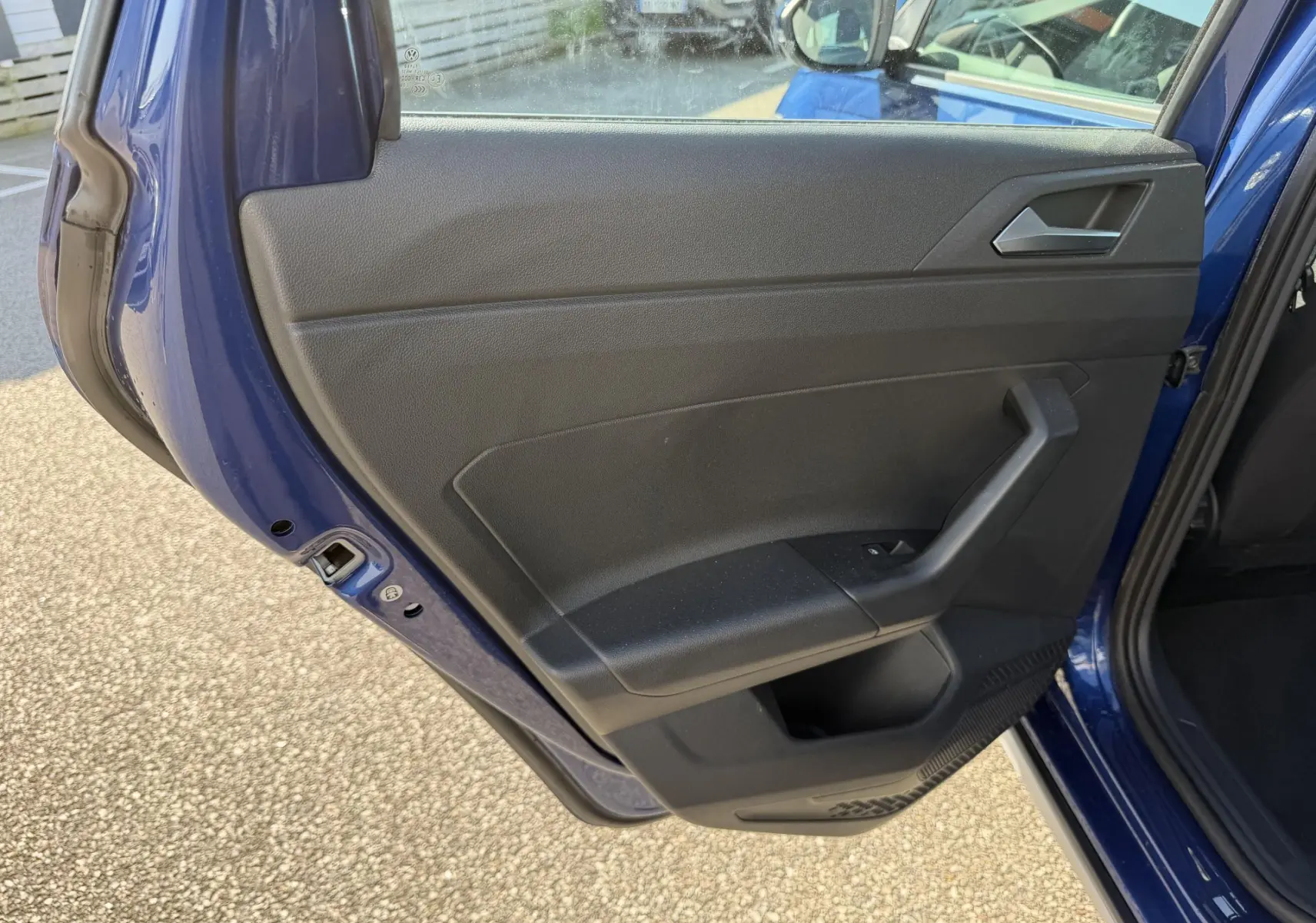 Vue intérieure de la porte arrière gauche bleu métallisé du Volkswagen Taigo 2025 avec poignée et panneau noir.