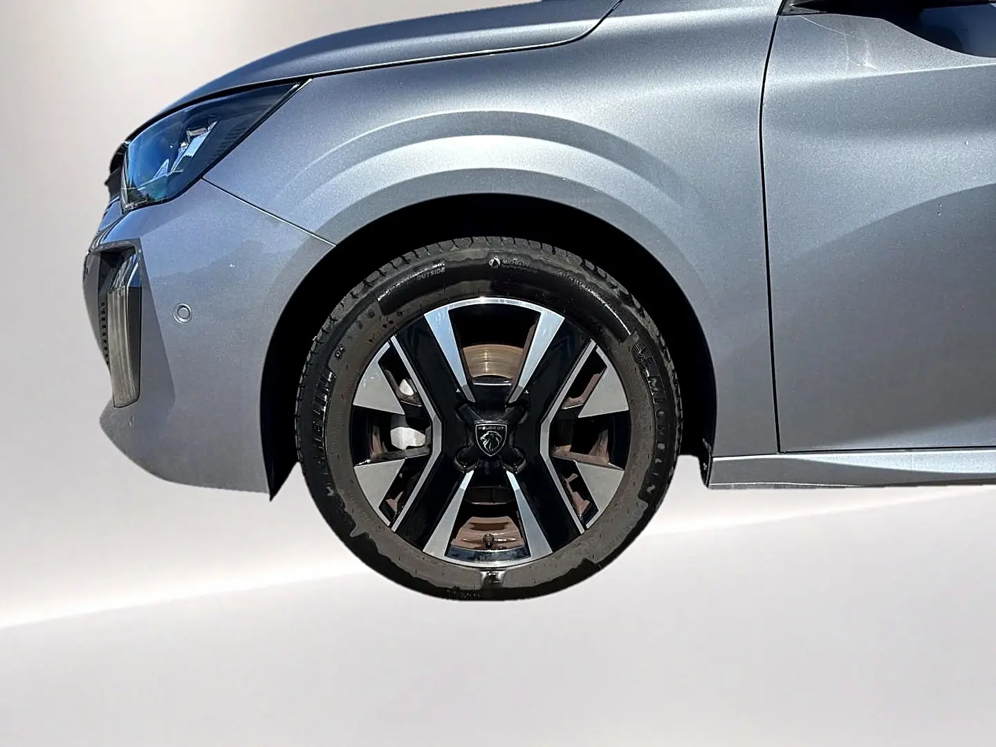 Gros plan sur la roue avant gauche et l'aile avant gris artense de la Peugeot 208 1.2 100 allure 2025.