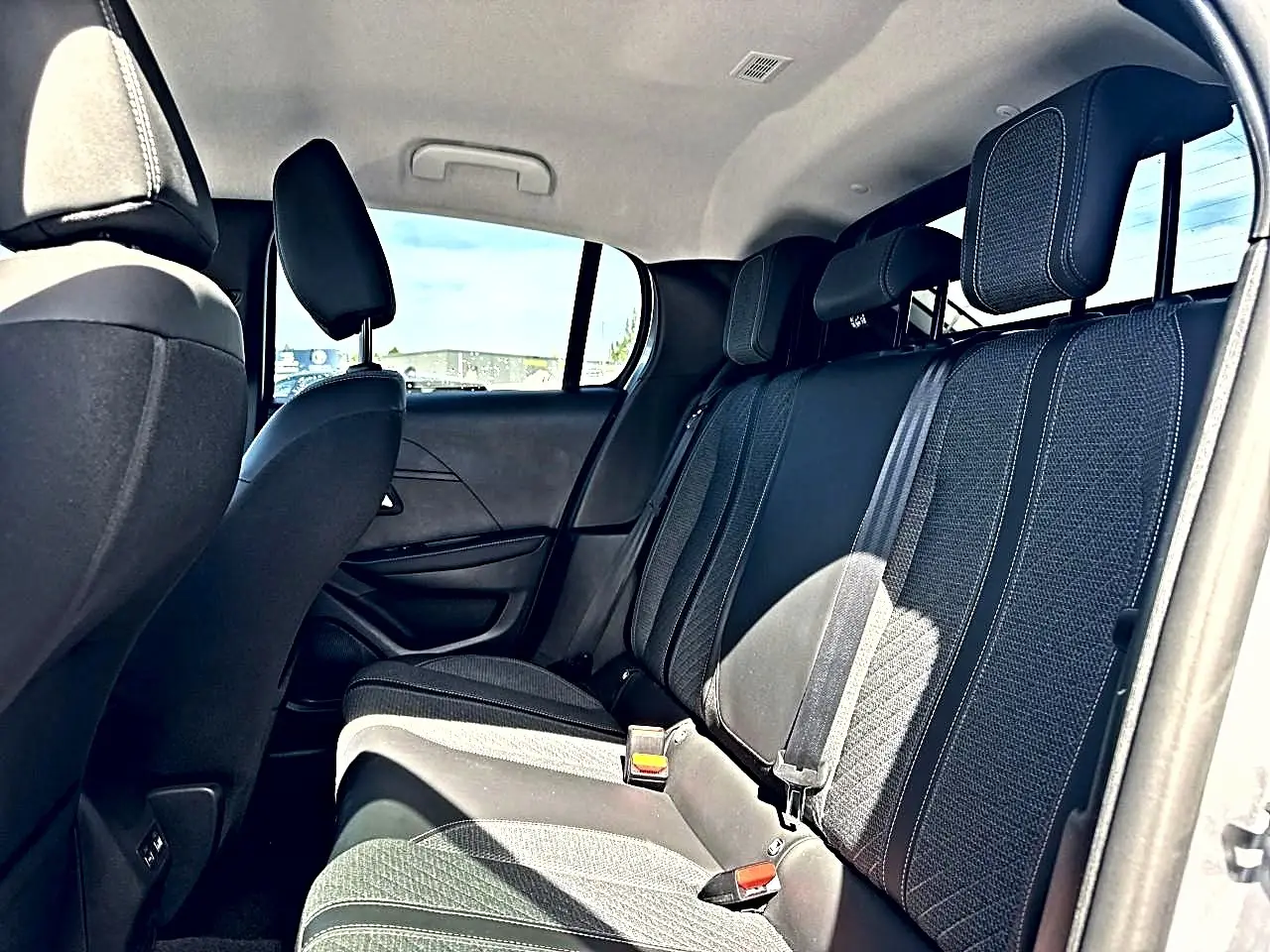 Vue intérieure côté droit sur la banquette arrière en tissu gris foncé de la Peugeot 208 1.2 100 Allure 2025.