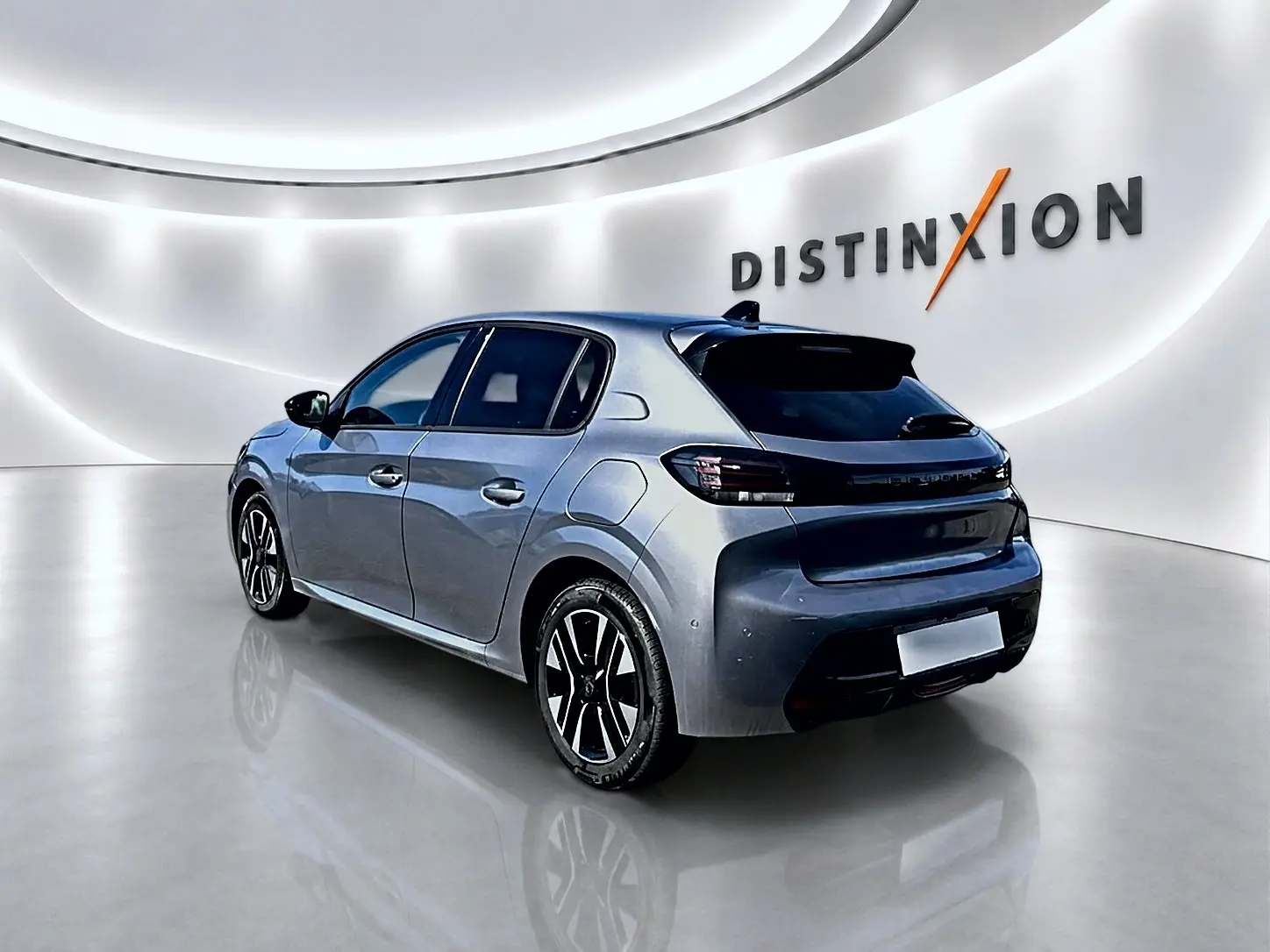 Peugeot 208 gris artense vue 3/4 arrière droit dans un showroom avec jantes alu et vitres teintées.