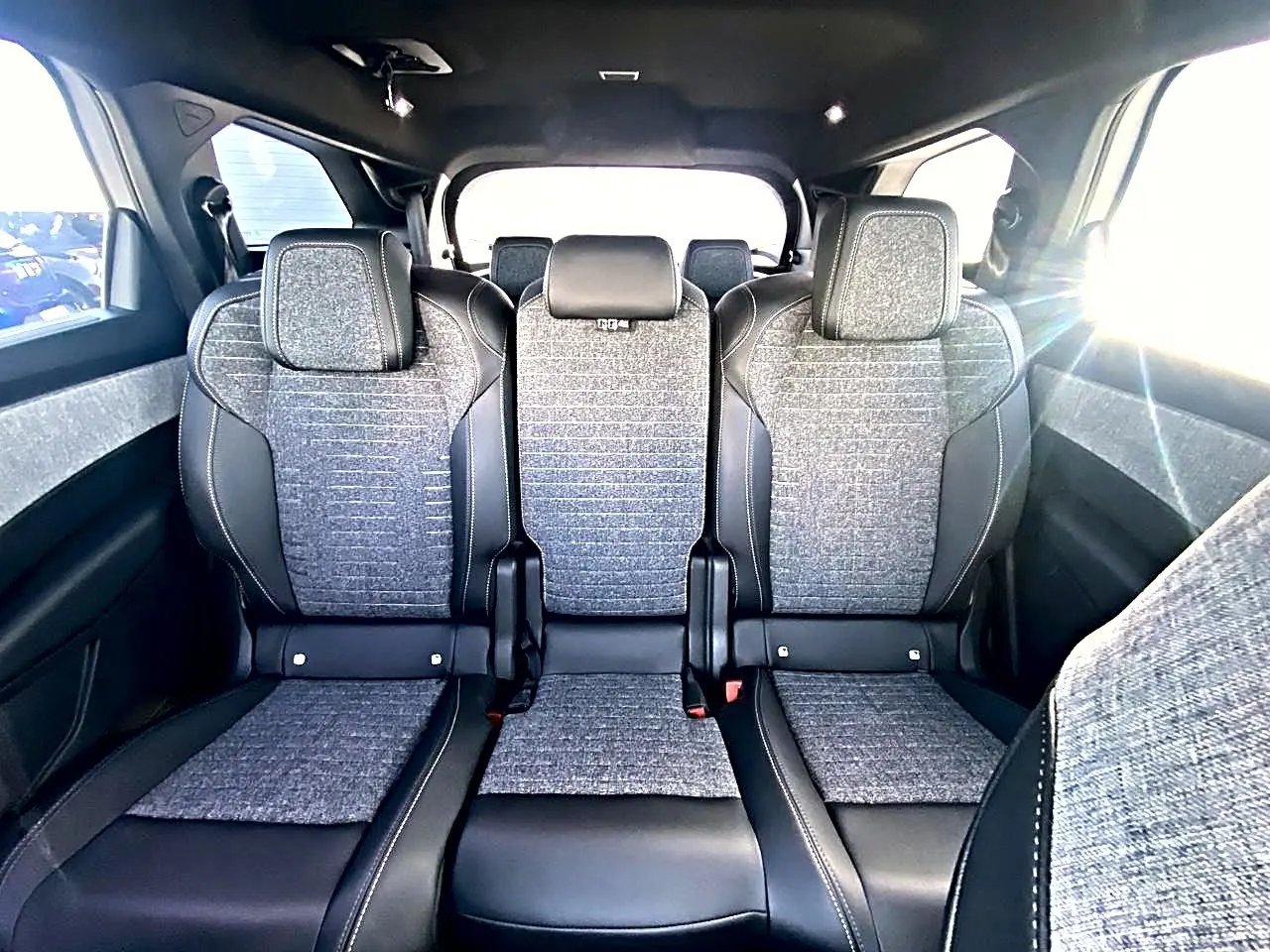 Vue intérieure des trois sièges arrière en tissu gris et cuir noir du Peugeot 5008 Hybrid 145 allure e-dcs6 blanc.