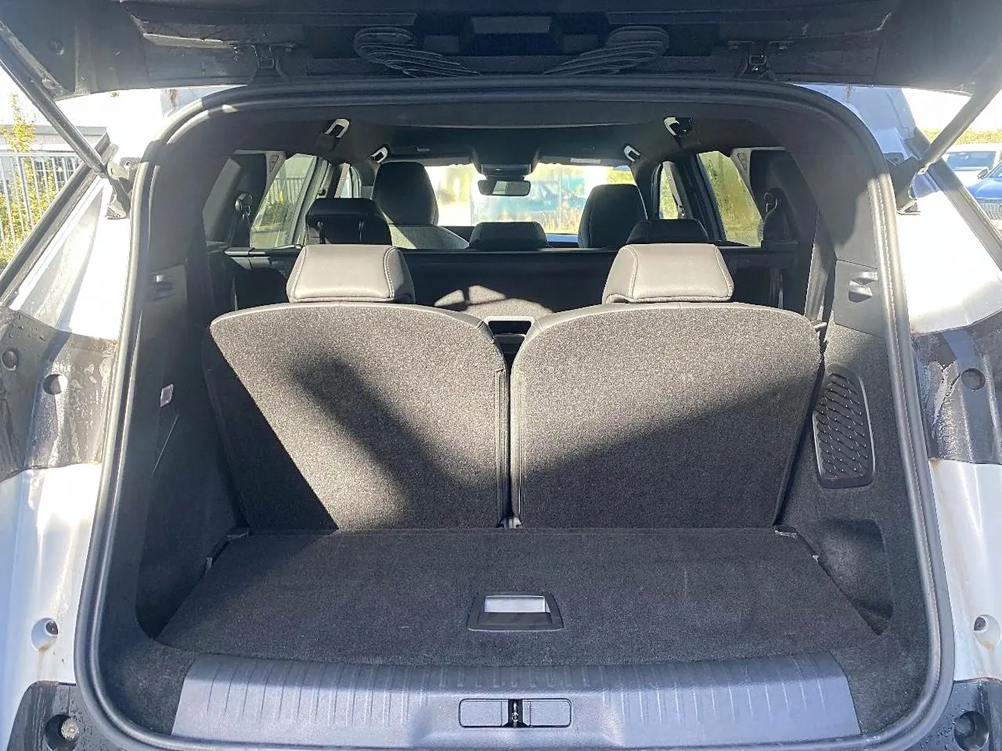 Coffre ouvert d’un Peugeot 5008 blanc, vue arrière montrant les sièges rang 3 relevés et l’habitacle intérieur.