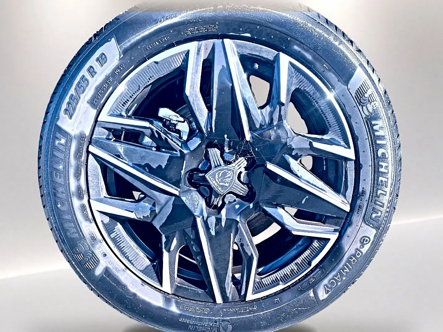 Gros plan sur la jante alu noire et argentée de la Peugeot 5008 Hybrid 145 allure e-dcs6 blanche, pneu Michelin 225/55 R19.