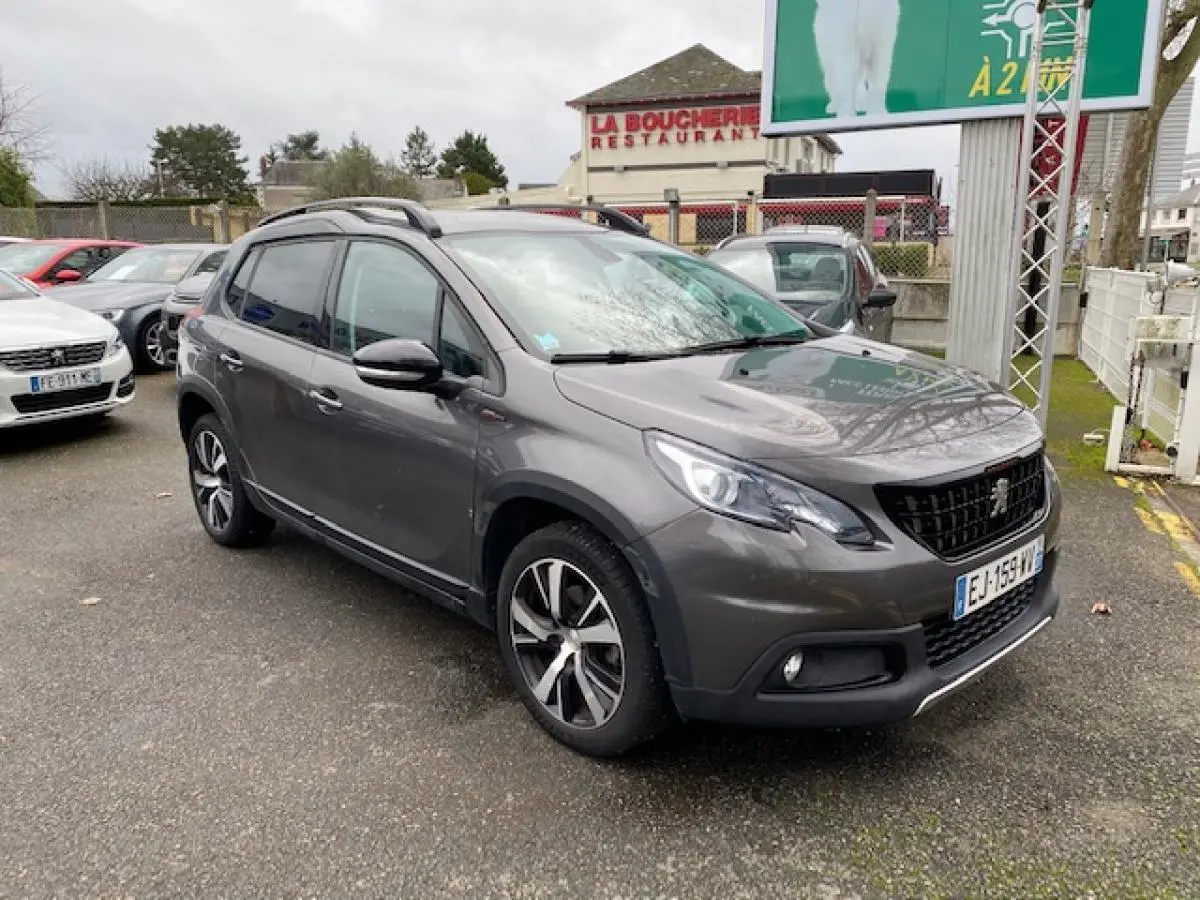 Peugeot 2008 gris foncé vue 3/4 avant droit avec jantes alliage 17 pouces et barres de toit noir brillant.