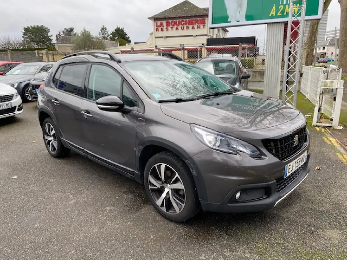 Peugeot 2008 gris foncé vue 3/4 avant droit, avec jantes alliage 17 pouces et barres de toit noir brillant.