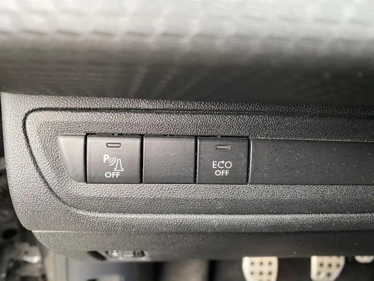 Gros plan sur les boutons de commande du tableau de bord du Peugeot 2008 gris foncé, avec fonction parking et mode ECO désactivés.