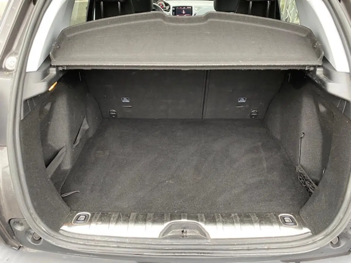 Coffre ouvert d'un Peugeot 2008 gris foncé, vue arrière montrant l'espace de chargement vide et la plage arrière relevée.