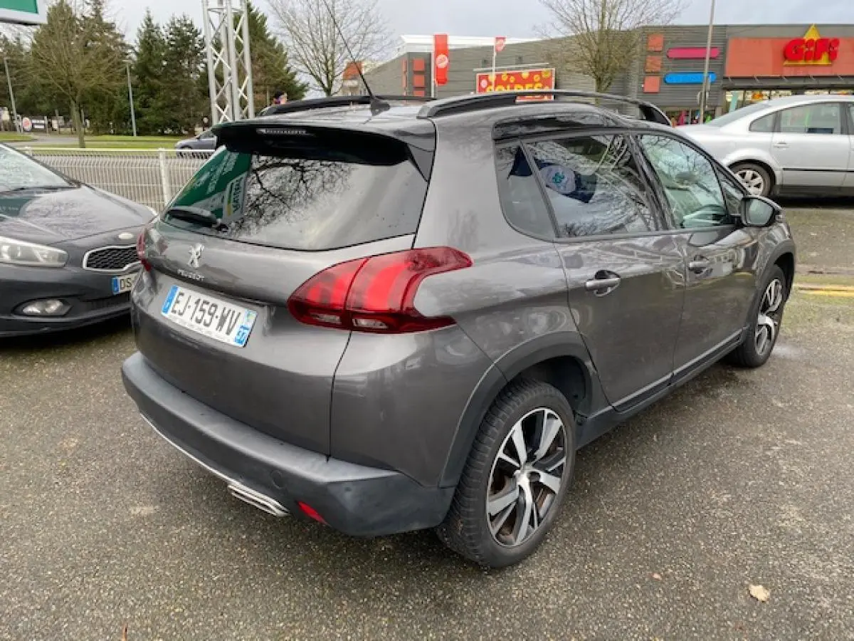 Peugeot 2008 gris foncé vue 3/4 arrière droit avec jantes alliage 17 pouces et barres de toit noir brillant.