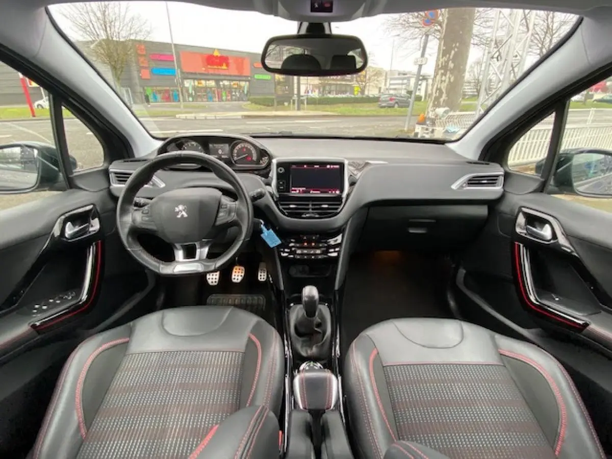 Intérieur Peugeot 2008 GT Line 2017 vu de face, sièges noirs avec surpiqûres rouges et volant compact sport.