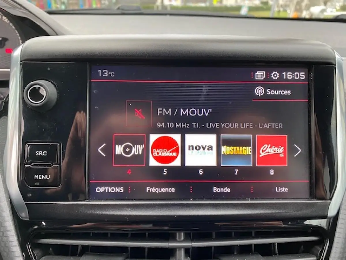 Écran tactile central du Peugeot 2008 gris foncé de 2017 affichant les stations radio FM en intérieur.