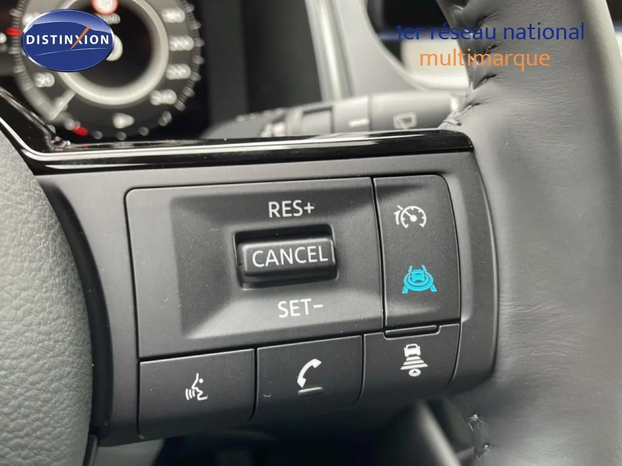 Gros plan sur les commandes au volant du Nissan Qashqai gris, avec régulateur de vitesse et assistance active visibles.