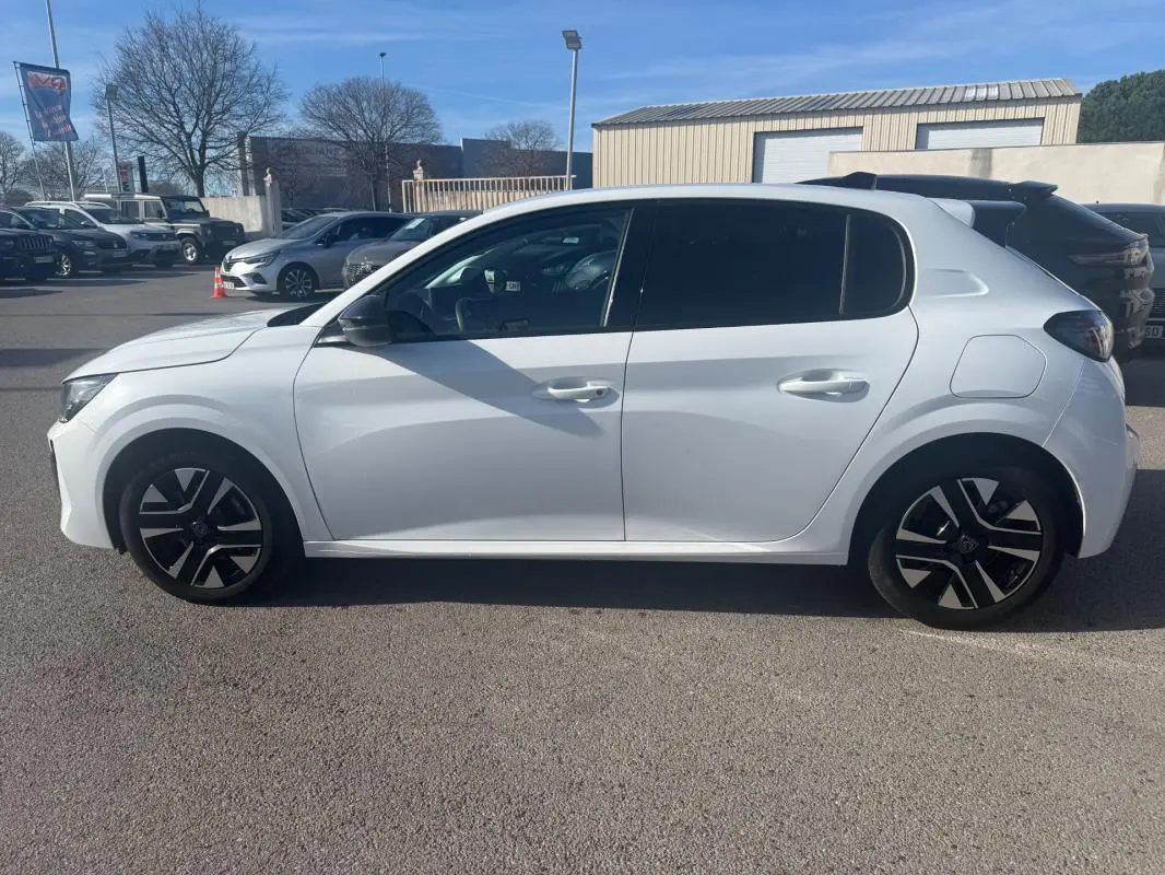 Vue latérale côté gauche d'une Peugeot 208 Hybrid 110 blanche avec jantes noires et détails modernes, modèle 2024.