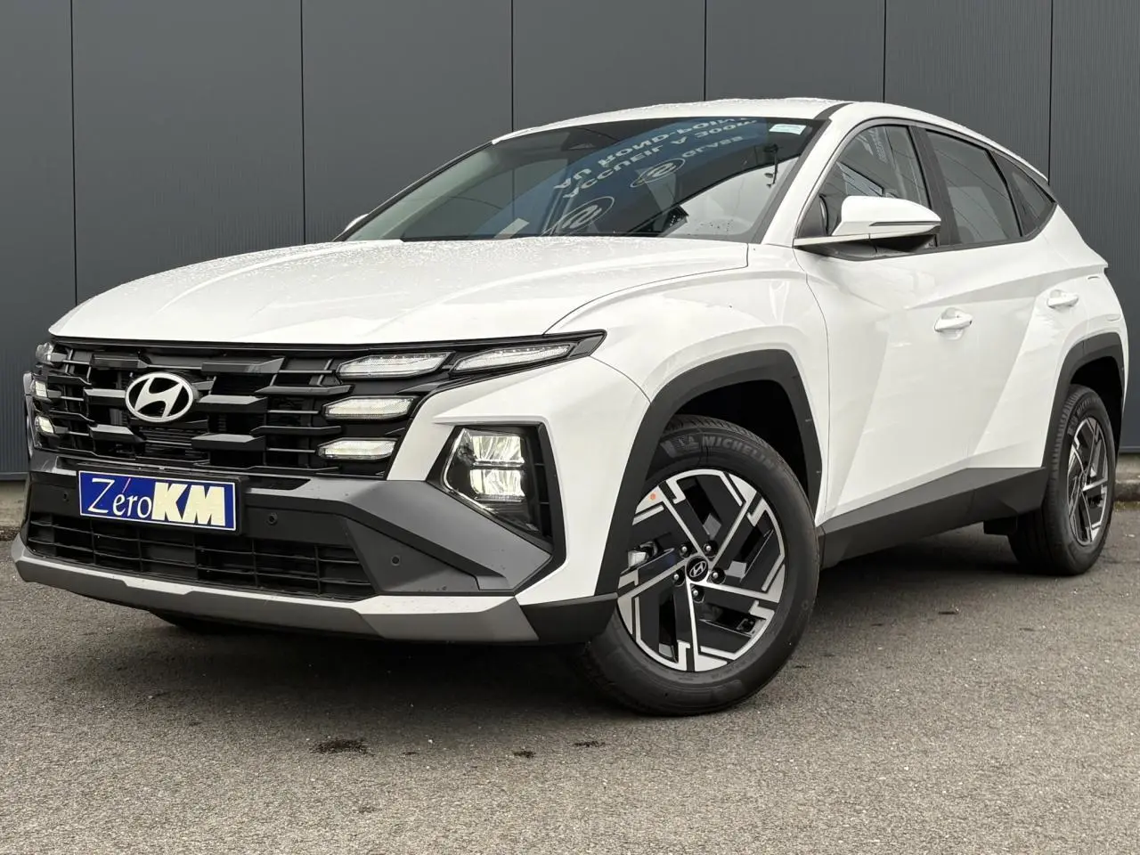 Hyundai Tucson 1.6 T-GDI Hybrid blanc Serenity vue 3/4 avant avec jantes alliage et calandre noire.