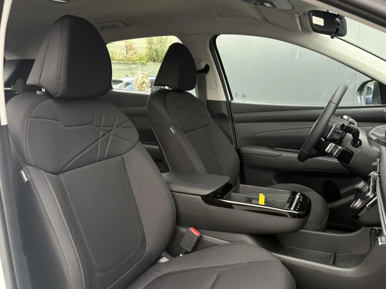 Vue intérieure côté gauche du Hyundai Tucson 2026 avec sièges avant noirs et console centrale moderne.