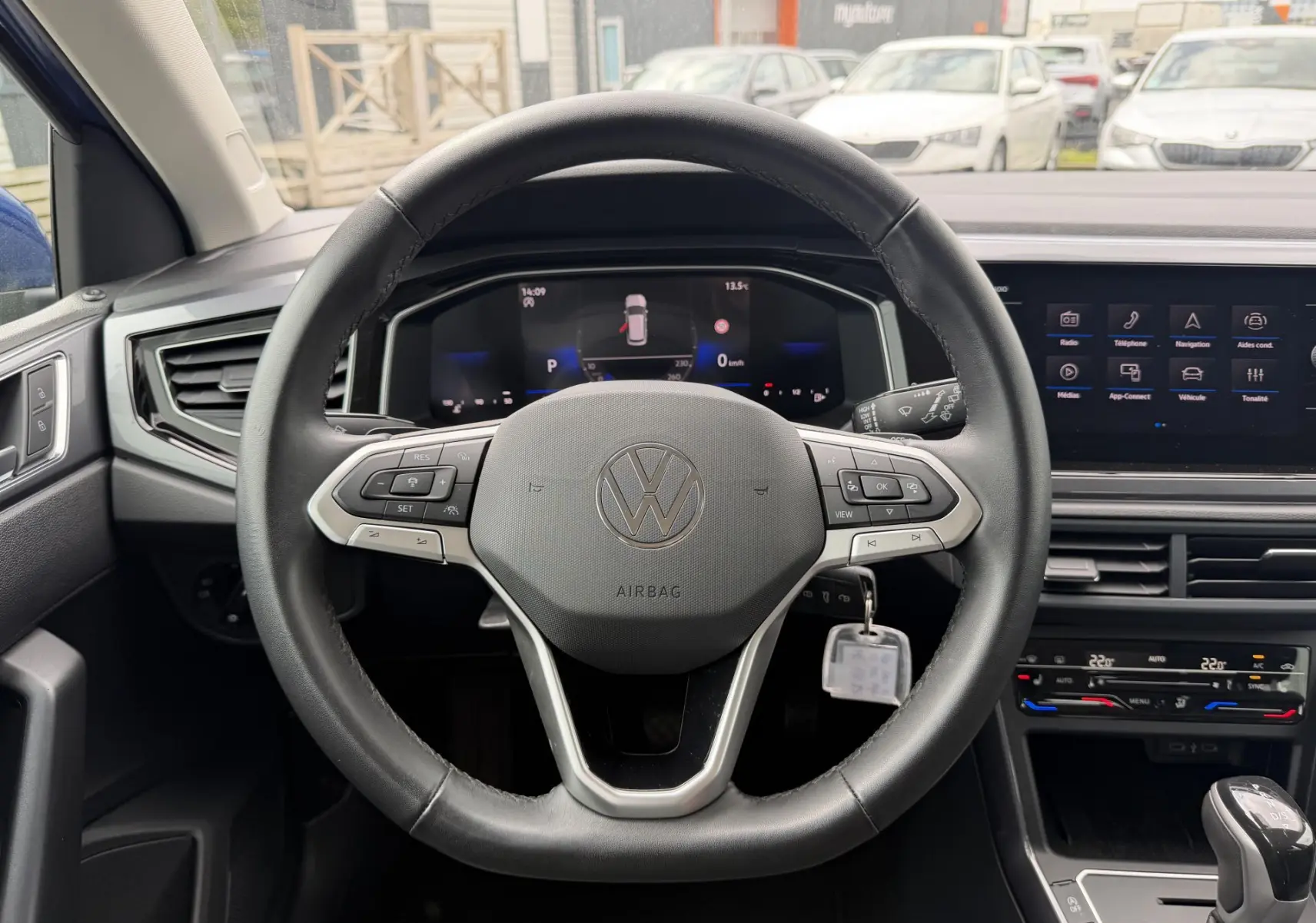 Vue intérieure centrée sur le volant cuir multifonctions d'une Volkswagen Polo 2025 avec tableau de bord digital et écran tactile.