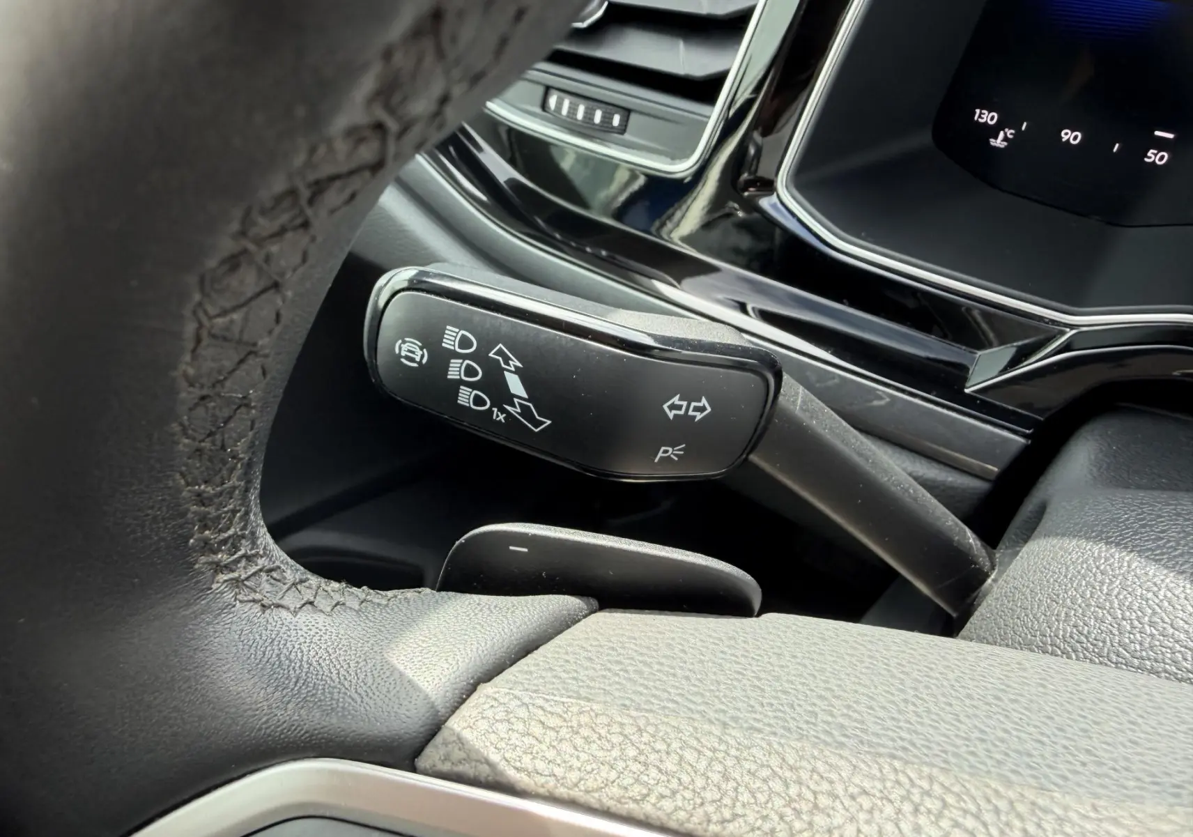 Gros plan sur le commodo de clignotant noir à gauche du volant cuir dans l’habitacle de la Volkswagen Polo bleue 2025.