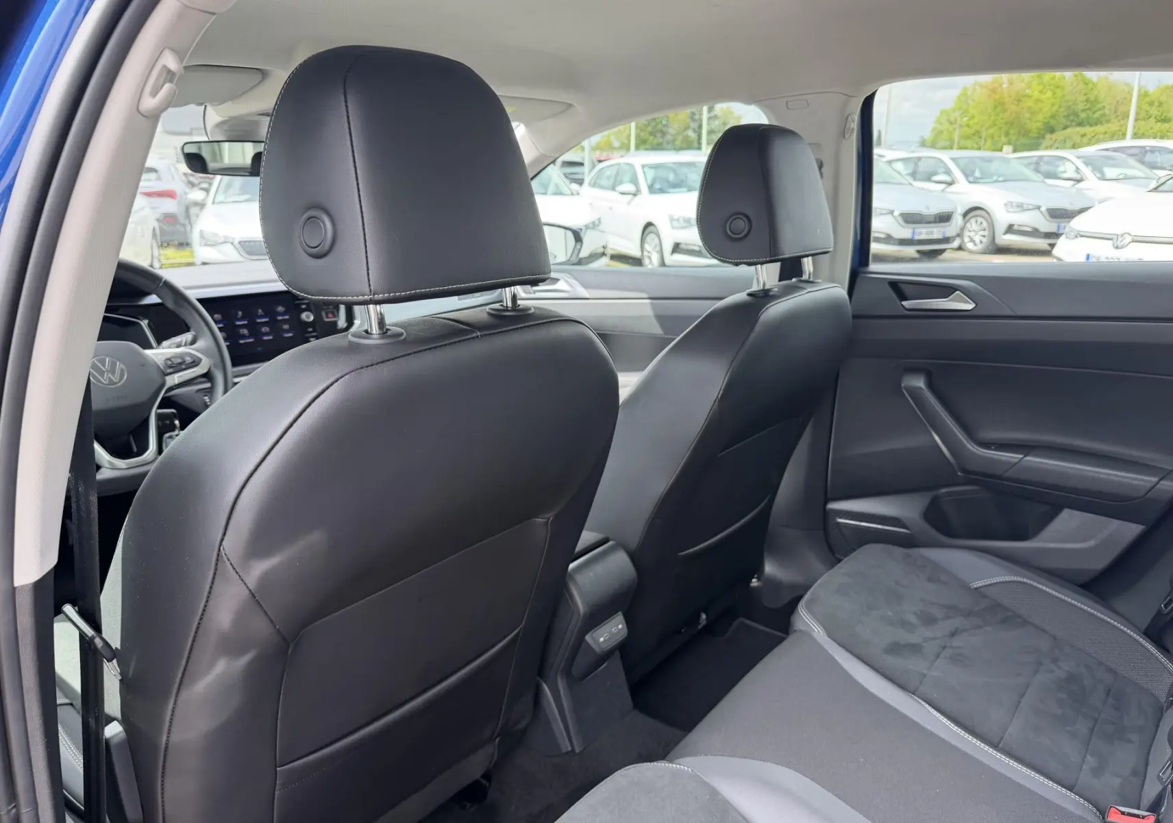Vue intérieure arrière de la Volkswagen Polo 2025 bleu, montrant les sièges avant en cuir noir et la banquette arrière.