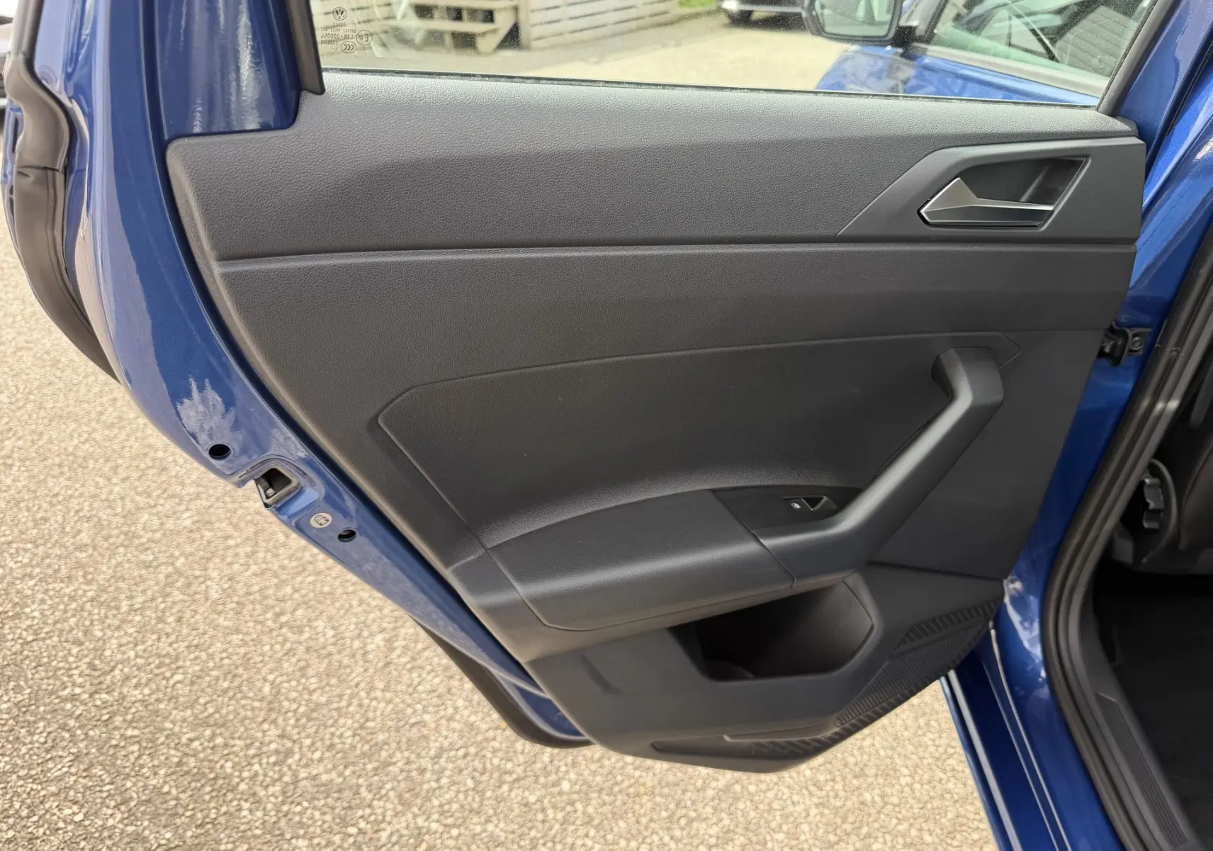 Vue rapprochée de la porte arrière gauche bleue d'une Volkswagen Polo 2025 avec garniture intérieure noire.