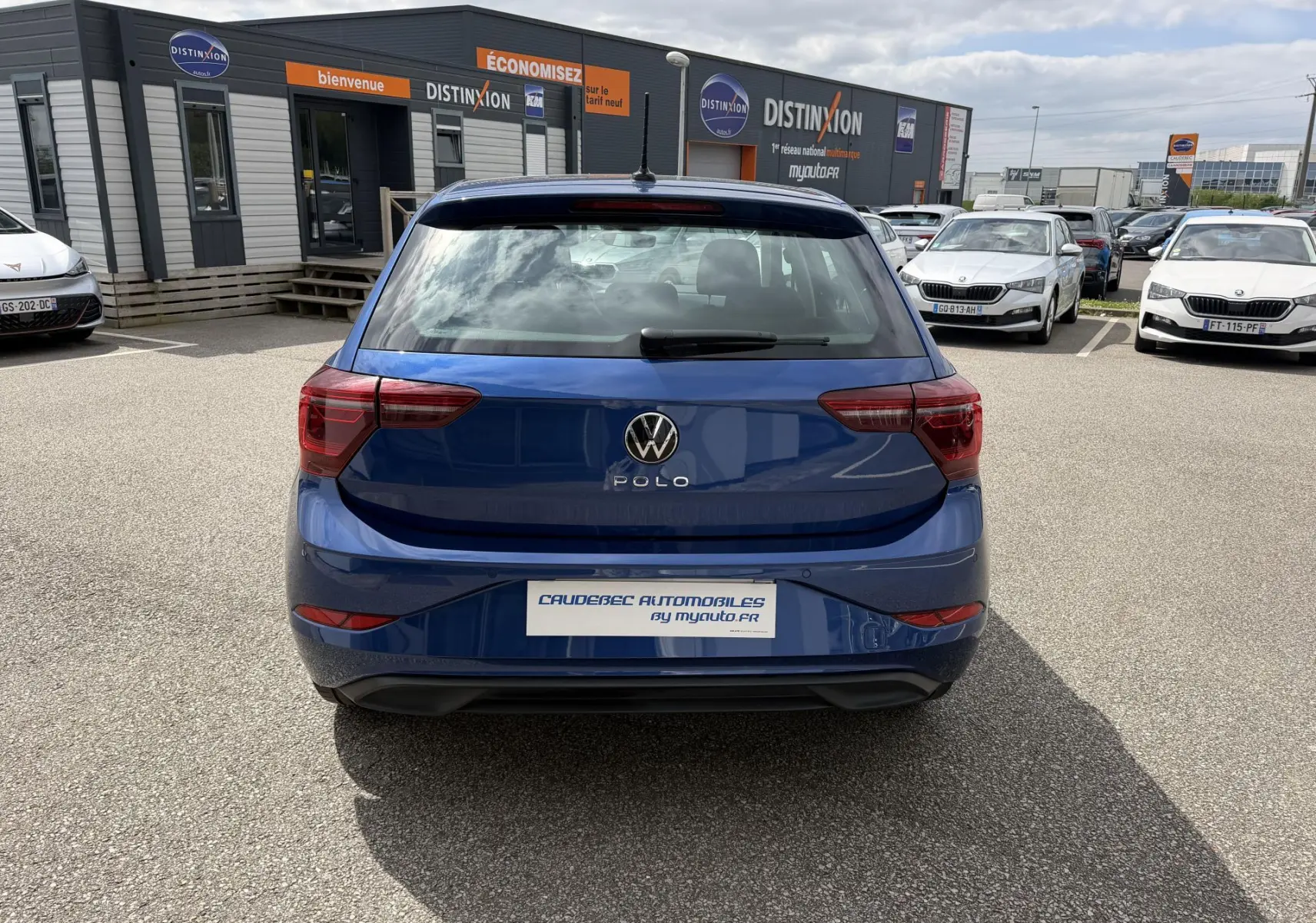 Vue arrière d'une Volkswagen Polo bleue métallisée 2025 stationnée devant un concessionnaire Distinxion.