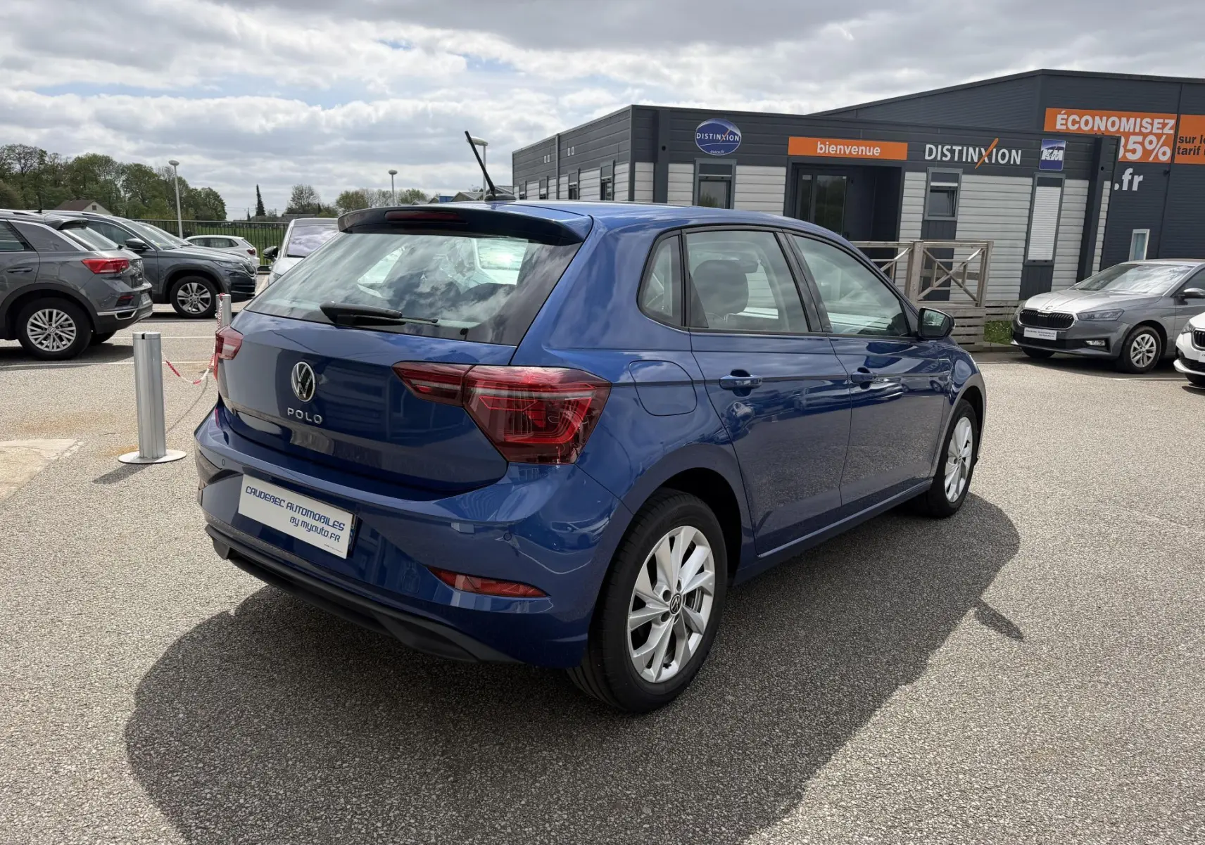 Volkswagen Polo bleue vue en 3/4 arrière droit sur parking, avec jantes alliage et feux arrière LED.