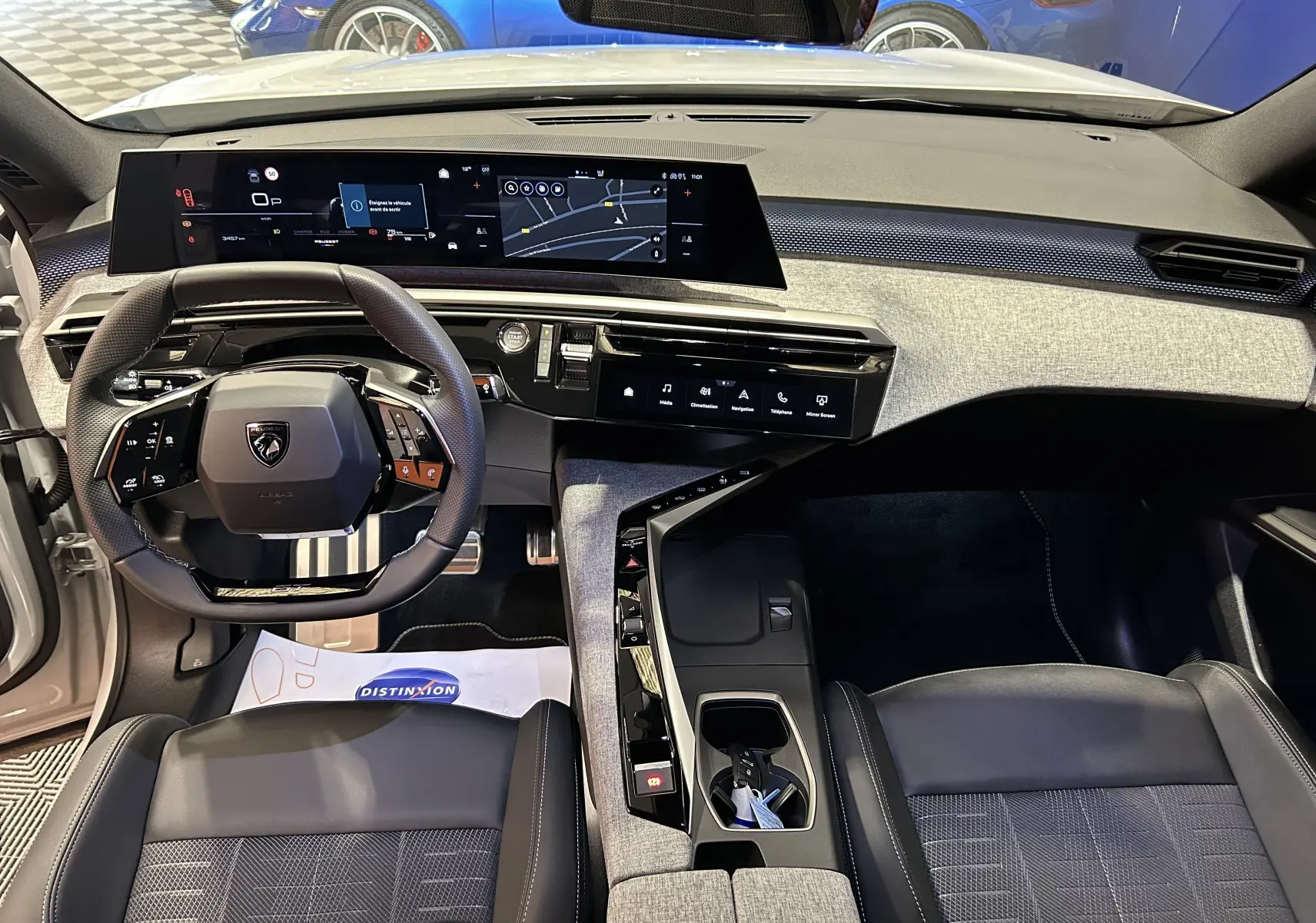 Vue intérieure du poste de conduite du Peugeot 3008 blanc Okenite, avec tableau de bord numérique et volant multifonction.