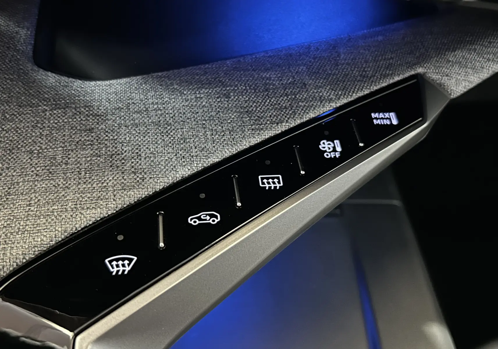 Gros plan sur la commande tactile de la climatisation avec éclairage blanc, intérieur tissu gris du Peugeot 3008 Hybrid 2025.