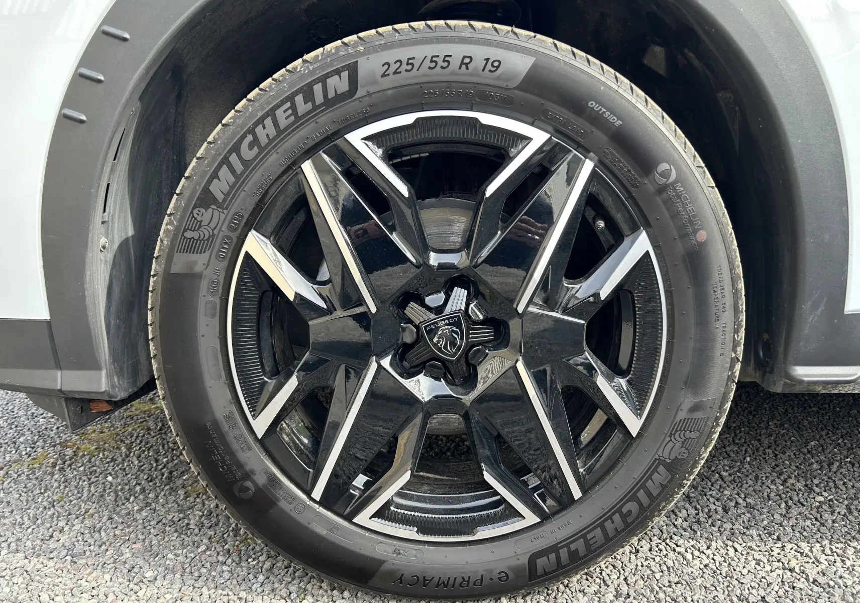 Gros plan sur la roue avant droite d’un Peugeot 3008 blanc Okenite avec jante alliage noire et détails argentés.