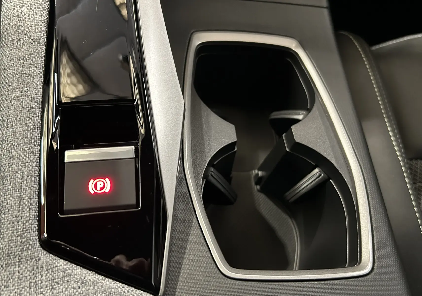 Gros plan intérieur sur la console centrale du Peugeot 3008 Hybrid blanc, avec frein à main électronique et porte-gobelets.