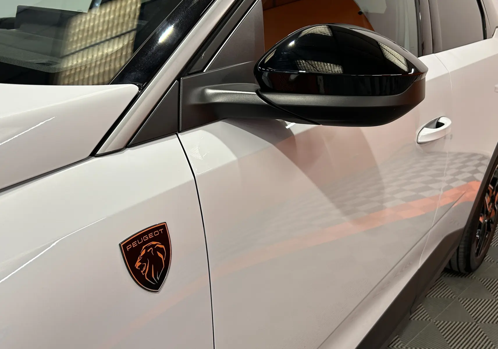 Gros plan sur le côté gauche blanc Okenite du Peugeot 3008 III Hybrid avec rétroviseur noir et logo lion orange.