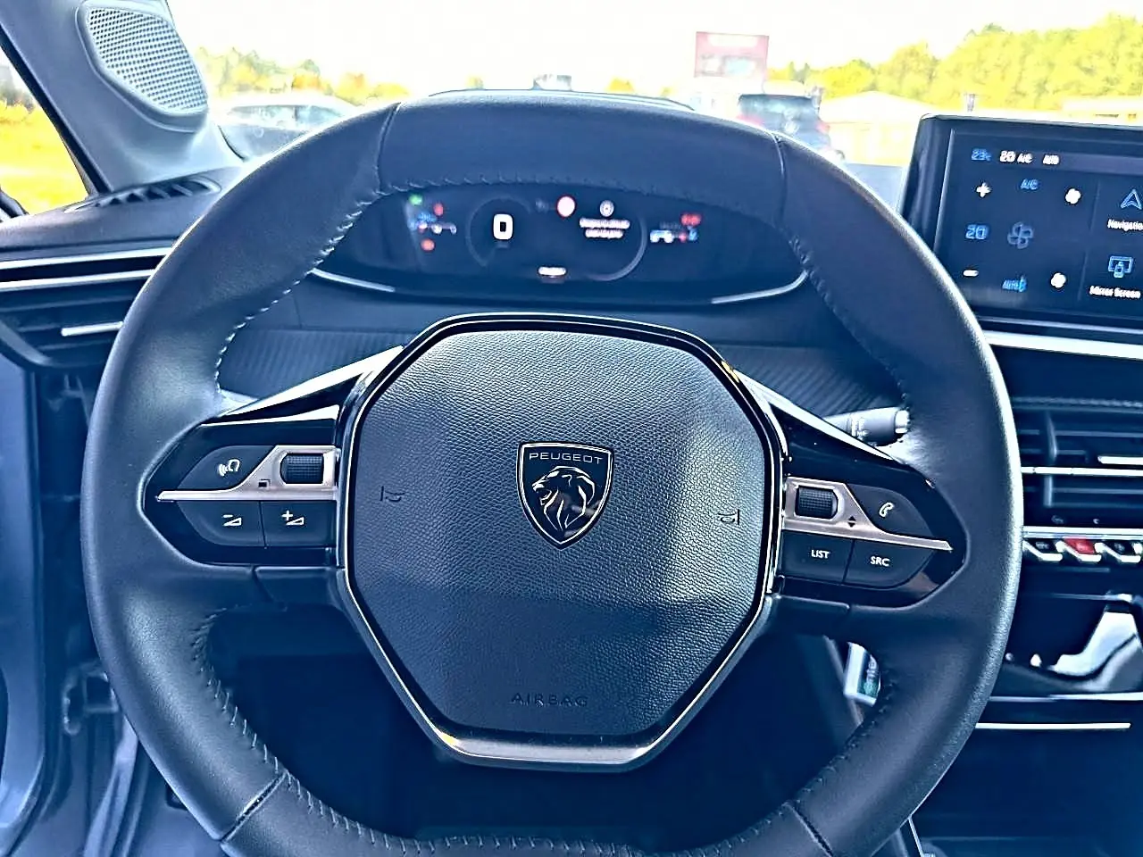 Vue rapprochée du volant noir de la Peugeot 208 1.2 100 Allure avec tableau de bord numérique et écran tactile.