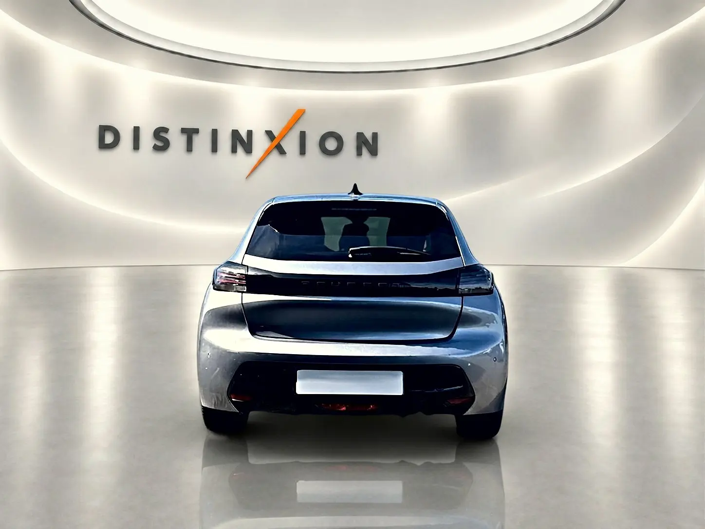 Vue arrière centrée de la Peugeot 208 1.2 100 Allure gris Artense dans un showroom lumineux avec logo Distinxion.