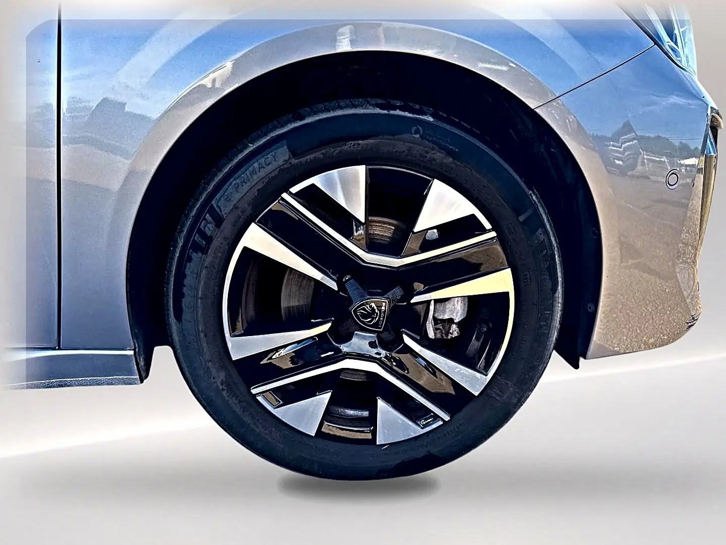 Gros plan sur la roue avant droite de la Peugeot 208 1.2 100 Allure gris Artense avec jante alu bicolore.