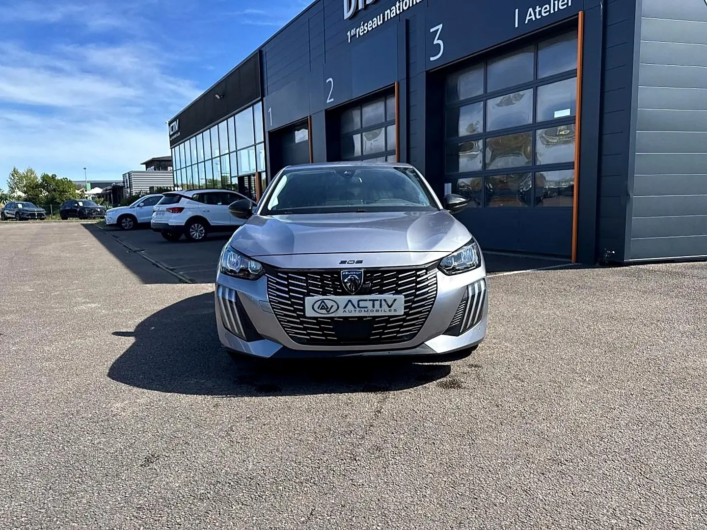 Peugeot 208 gris Artense vue de face, mettant en valeur la calandre distinctive et les phares LED.