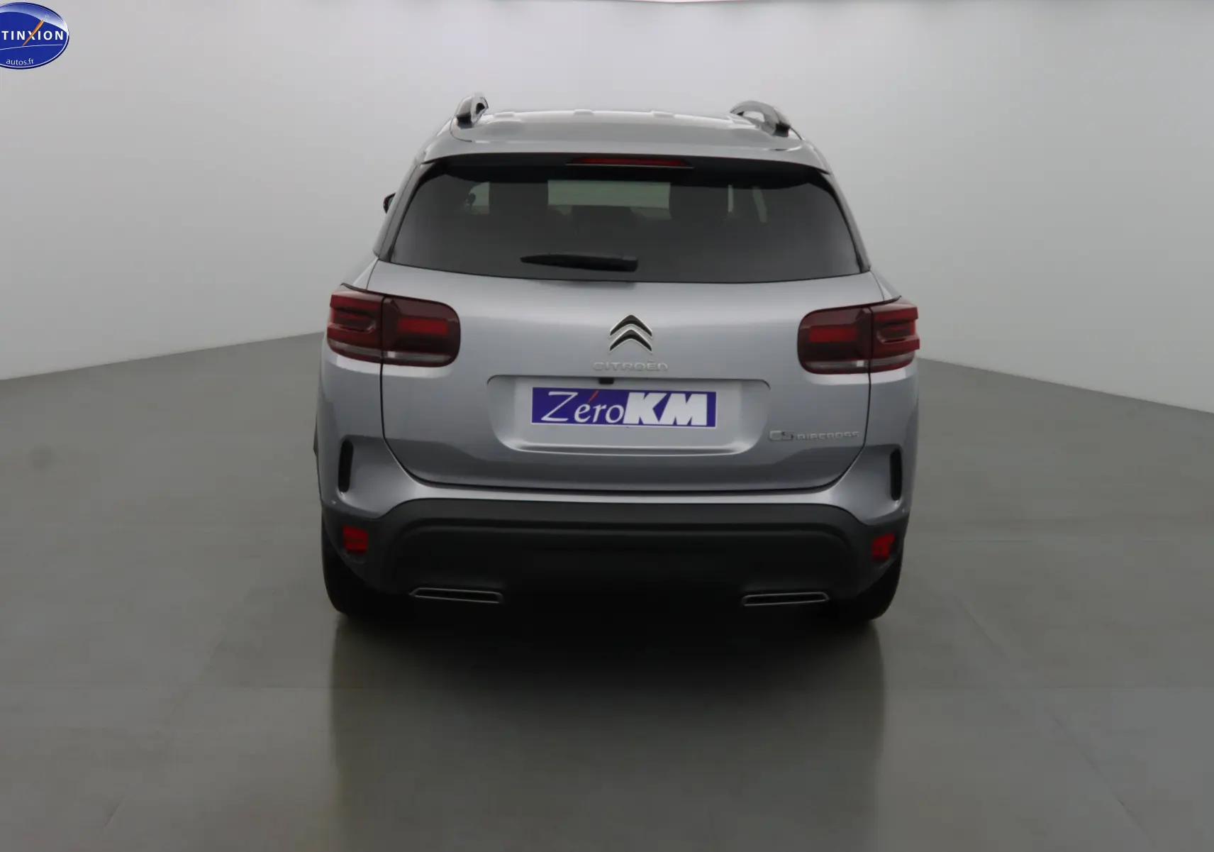 Vue arrière d'un Citroën C5 Aircross gris Artense métal avec feux arrière foncés et double sortie d'échappement intégrée.