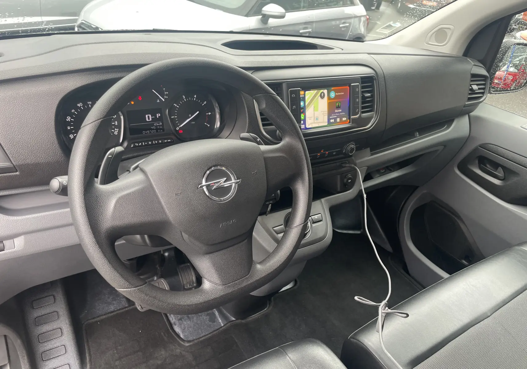 Vue intérieure côté conducteur de l'Opel Vivaro Fourgon 2020, tableau de bord noir avec écran tactile et volant multifonction.