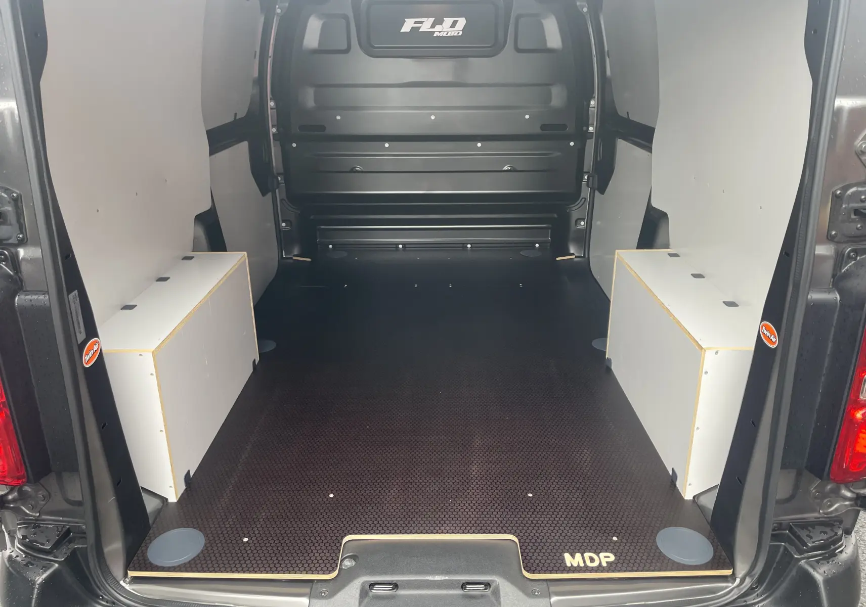 Vue arrière de l Opel Vivaro Fourgon gris Pierre de Lune métallisé, montrant l espace de chargement vide avec aménagements latéraux blancs.