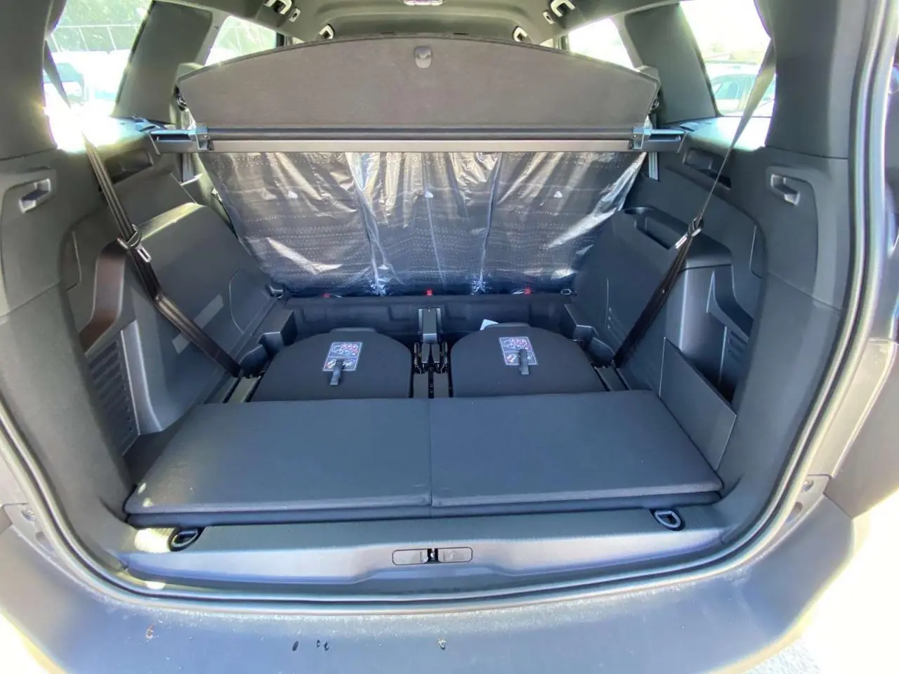 Coffre ouvert du Peugeot 5008 gris platinium, montrant les sièges arrière rabattus et la plage arrière déployée.