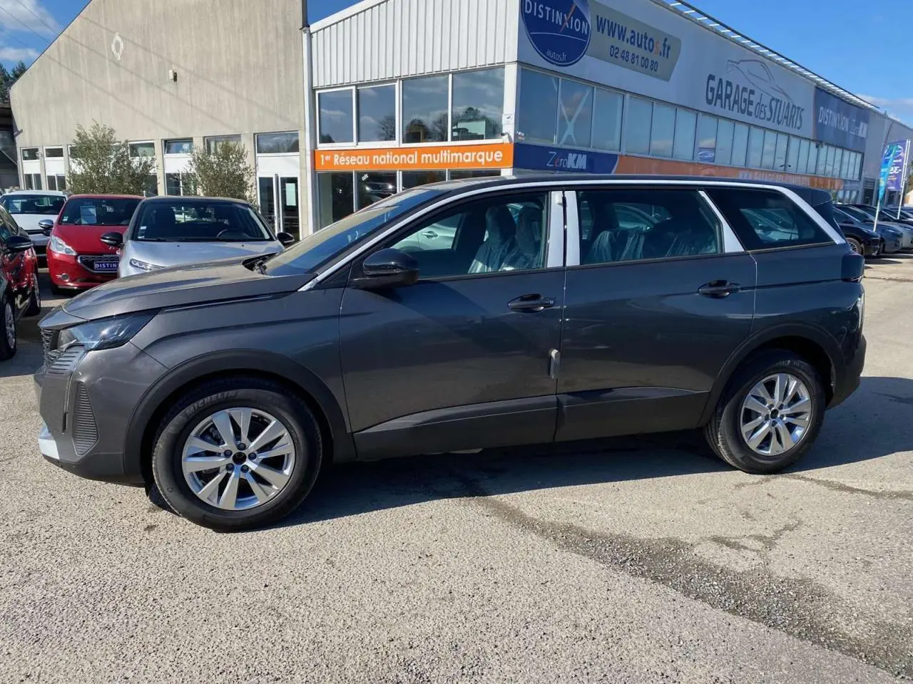 Profil côté gauche d'un Peugeot 5008 gris platinium métallisé, avec jantes alliage 17 pouces, stationné en extérieur.